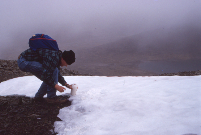 Simon fills his water bottle with snow on the way up to the summit of Montana Mountain, Yukon.