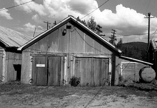 Facade of the Garage and Storage Building at Bear Creek, showing the building's simple, rectangular form, gable roofs and large double doors, 1988. Photo by Parks Canada.