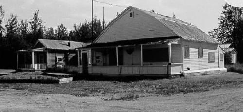 Corner view of the V.I.P. Guest House, showing the distinctive gambrel-like shape of the roof and the front verandah, 1988. Photo by Parks Canada.