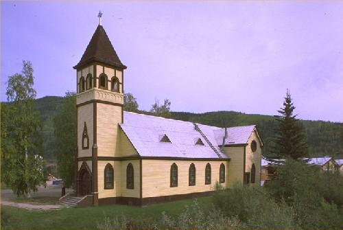 General view of St. Paul's Anglican Church, showing the rectangular massing under a steep gabled roof with truncated transepts, polygonal apse, and tower with pyramidal, bell-cast roof. Photo by Parks Canada.