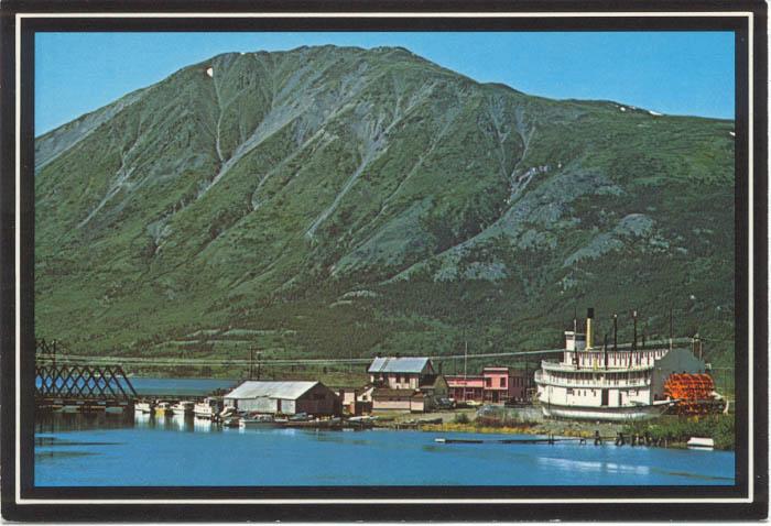 A historic postcard showing Carcross and the sternwheeler Tutshi from the highway bridge over the Nares River in the 1980s.