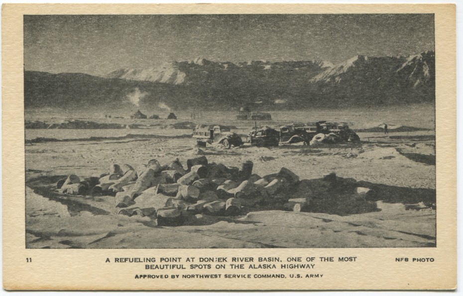 Alaska Highway postcard showing wrecked Army trucks and abandoned fuel barrels at the Donjek River in the winter, 1940s