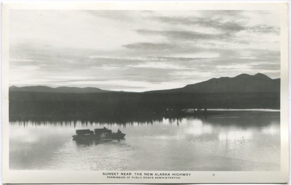Alaska Highway postcard showing a small boat pushing a barge with 2 Army trucks on it, 1940s