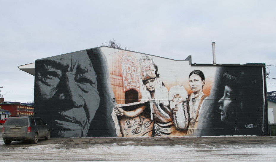 Mural by Colin Alxander of a First Nation family and two shadowed faces of a child and an elder, in Whitehorse, Yukon